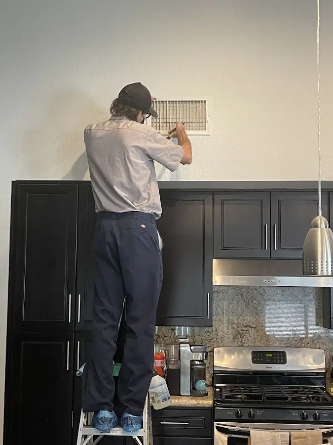 Technician inspecting an air vent during HVAC service in New Fairfield